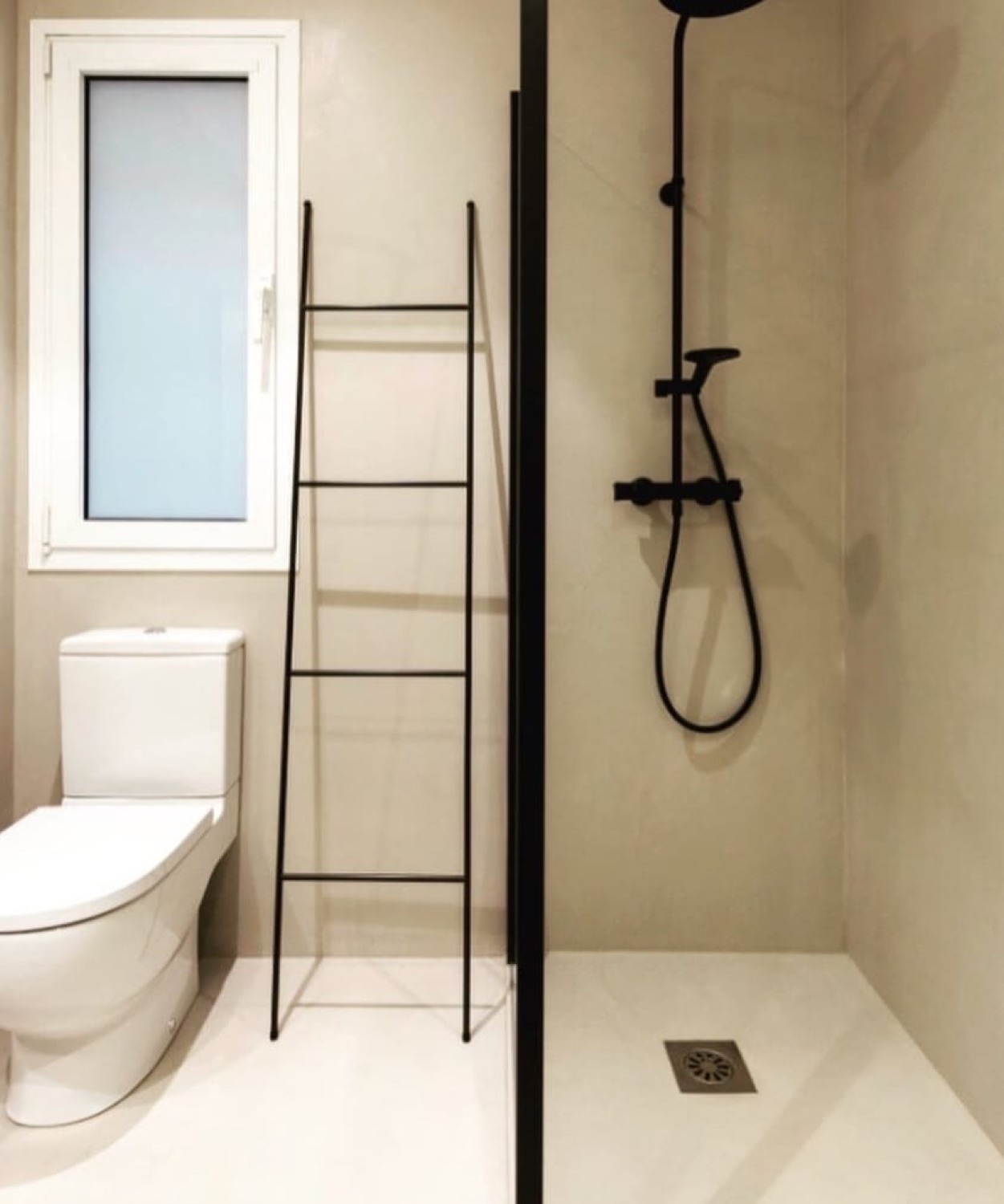 Baño en microcemento beige con ducha en negro