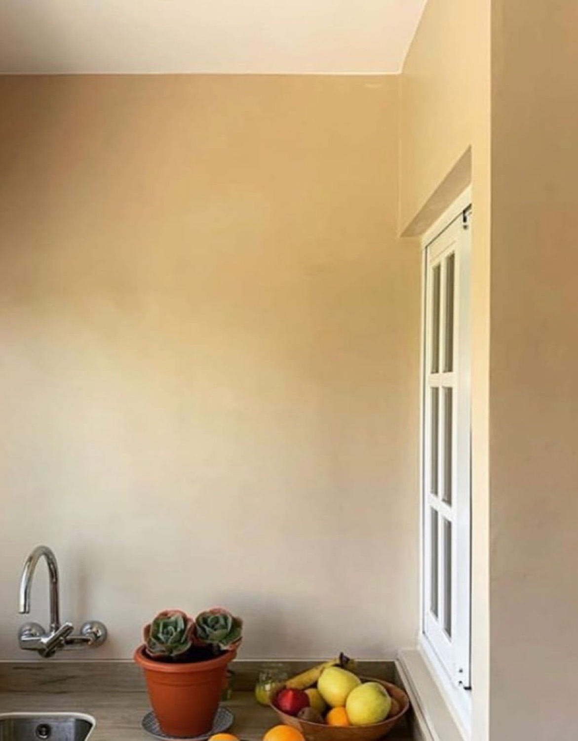 Cocina en microcemento beige con fregadero junto a ventana