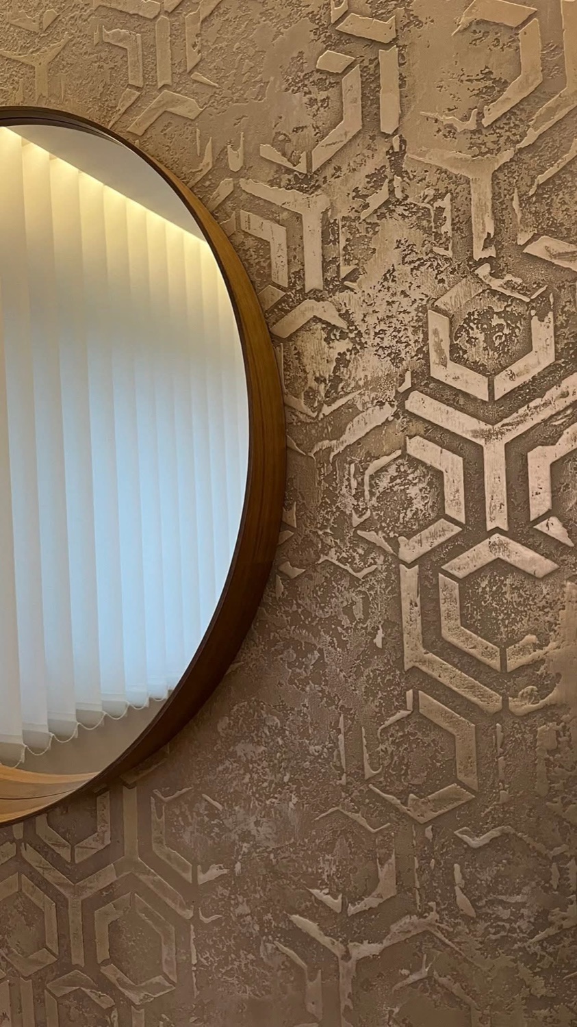 Detalle de pared con hexágonos junto a espejo redondo